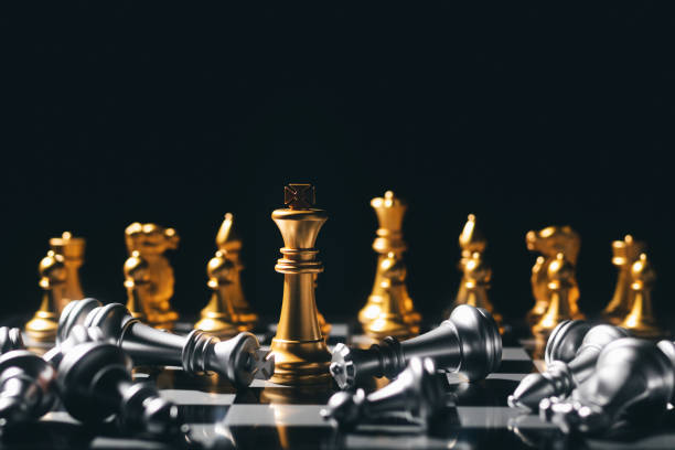 Close-up King standing on a chessboard. There's a falling chess in front, leadership. teamwork Business Team Challenges, Global Industry Winners. stock photo