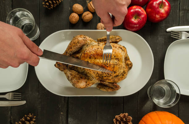 composizione della cena del ringraziamento, con pollo arrosto o tacchino e mano con un coltello che intaglia la carne. - thanksgiving dinner party feast day turkey foto e immagini stock