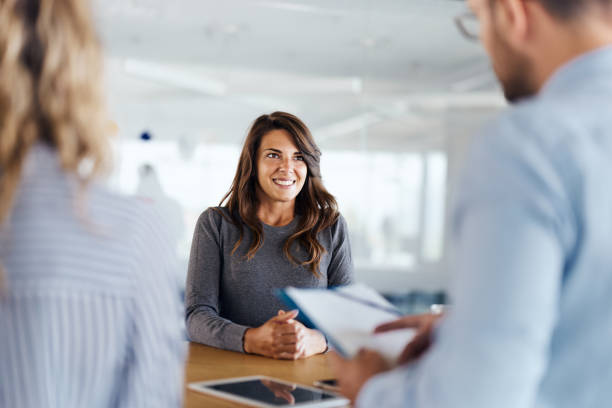 Happy female candidate on a job interview in the office. Young female candidate talking to human resource team during a job interview in the office. job interview stock pictures, royalty-free photos & images