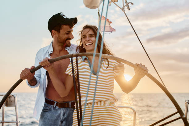 istock Young cheerful couple having fun while driving a yacht at sunset. 1437821017