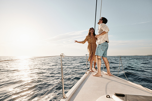 Cheerful couple having fun while dancing on a boat in summer day. Copy space.