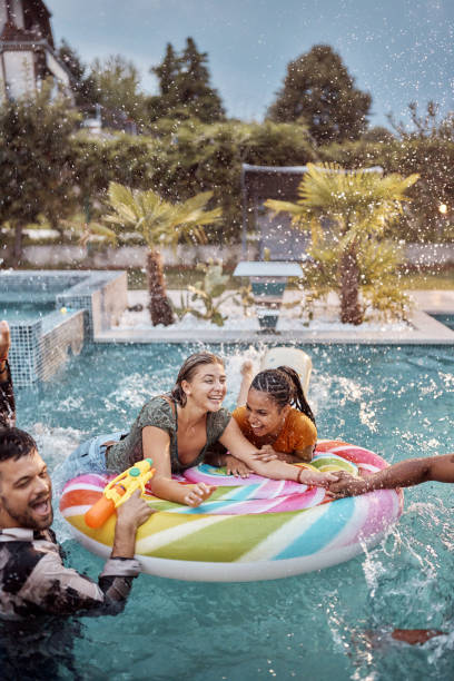 istock Cheerful friends having fun during summer day on a pool raft. 1437822402