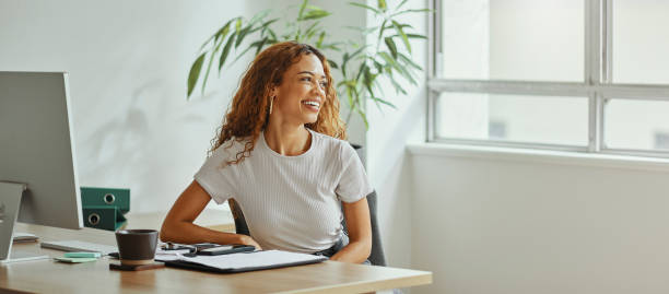 Black woman, modern finance office and smile by desk with corporate business financial document or accounting report. An African girl accountant, happy investment employee and international workplace mujer negra, oficina de finanzas moderna y pensando en el escritorio sobre la visión corporativa para las finanzas comerciales o las ganancias contables. contadora africana, una feliz empleada de la empresa y lugar de trabajo de inversión
