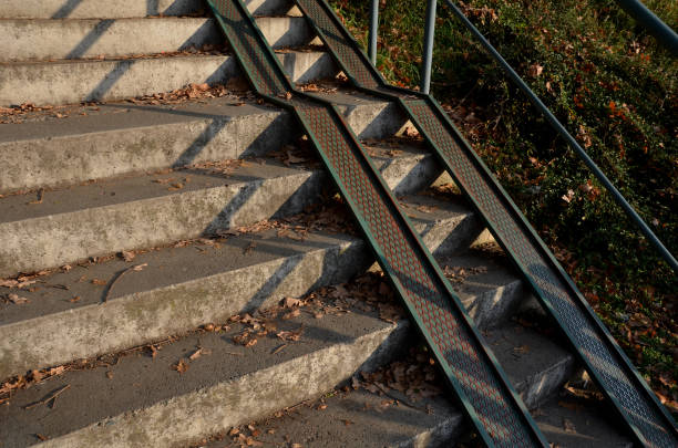 rampa combinada con una escalera de hormigón gris y una barandilla especialmente adaptada para sillas de ruedas. solución de seguridad de buen gusto para entrar en un parque de la ciudad. rieles de chapa - steep road footpath moving down fotografías e imágenes de stock