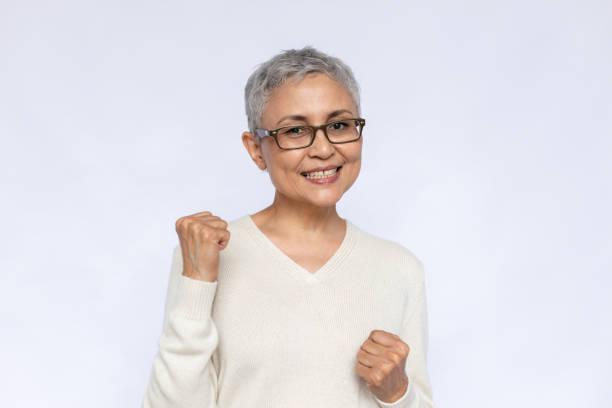 Portrait of happy senior woman making winning gesture stock photo