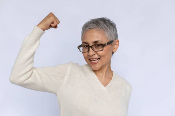 Portrait of happy senior woman showing arm bicep stock photo