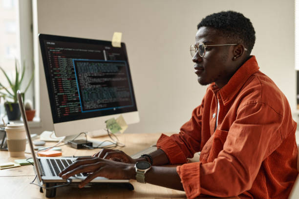 istock Side view of young black man in smart casualwear and eyeglasses decoding data 1437825806
