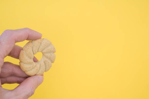 istock Hand holding a sun shaped cookie on yellow background with a copy space 1437825907