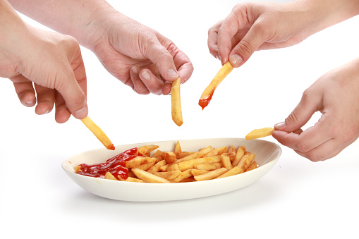 A closeup shot of people eating fries with ketchup