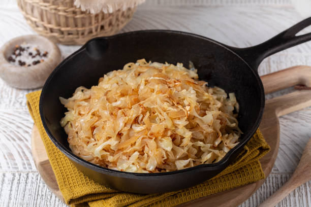 Pan fried Sauerkraut or Crauti. Finely cut white cabbage cooked with fried onion and white wine. White wooden table. stock photo