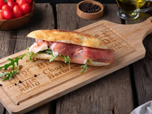 Italian panini sandwich with mortadella or Parma ham, multi grain baguette arugula and onion. Takeaway food
