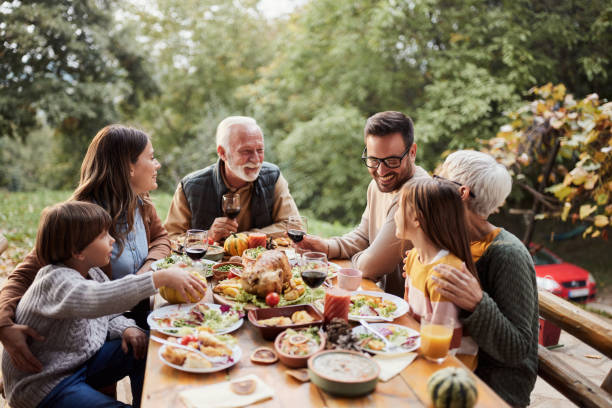 szczęśliwa wielopokoleniowa rodzina ciesząca się obiadem na tarasie. - multi family zdjęcia i obrazy z banku zdjęć