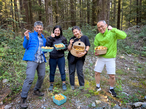 Multi-generation family with harvest of wild Chanterelle mushrooms from forest.  Bamfield, Vancouver Island, British Columbia, Canada