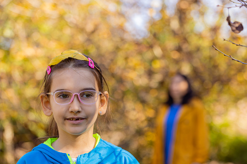 Smart little girl standing outdoors, wearing  blue jacket