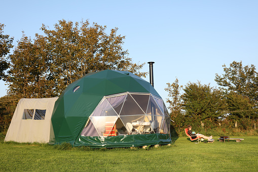 Cardigan, United Kingdom – September 13, 2020: Lit up dome tent in a glamping site. Wales, UK