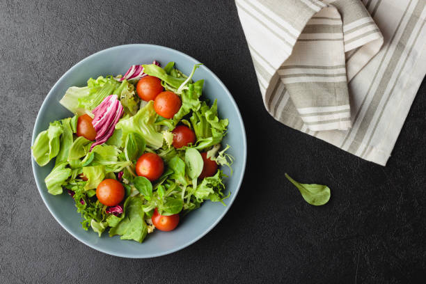 istock Green salad leaves in bowl on black table. 1437836170
