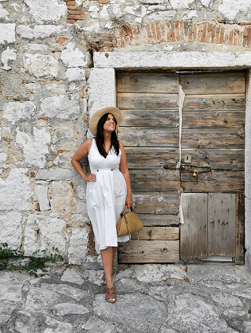 A vertical shot of a female standing on the stone walls and a wooden old door