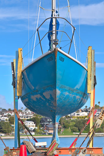 Auckland, New Zealand – July 29, 2019: Auckland / New Zealand - July 29 2019: View of blue yacht on dry dock stand being repaired