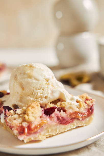 istock Delicious plum cake with crumble and ice cream on a white table 1437836958