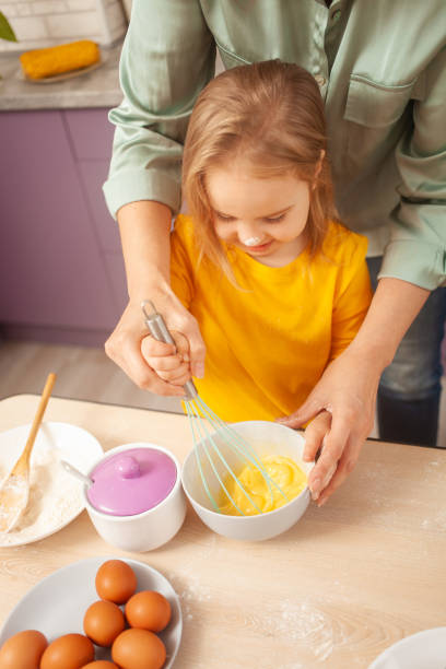 istock Mother and daughter cook pie in purple kitchen, training and development, interesting game and help. Happy family together. beats eggs 1437839434