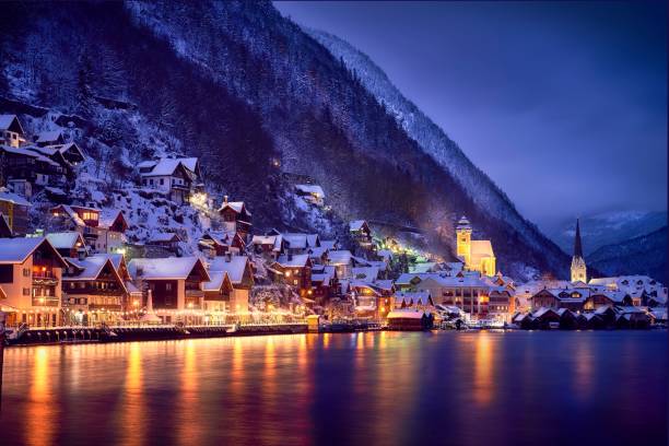 petite ville avec des rues illuminées pendant la nuit couvertes de neige près du lac hallstatt - salzkammergut photos et images de collection