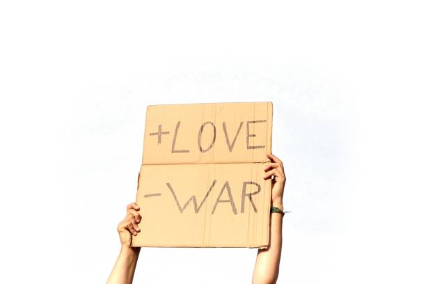 istock A Cardboard Signs saying More Love, Less War held by two hands on a white background 1437840472