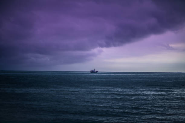 istock Single ship on the calm sea under the clouds in the evening 1437840574