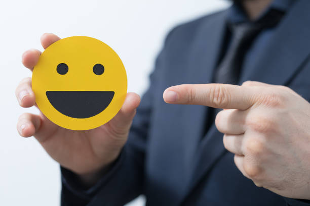 istock Hand in suit holding a smiley emoji and pointing to it 1437840914