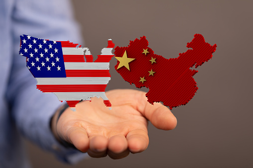 A hand holding the USA and Chinese flags