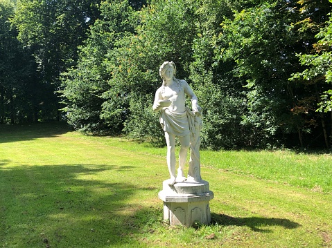 Adorable naughty cupid sculpture in a  freshly green garden