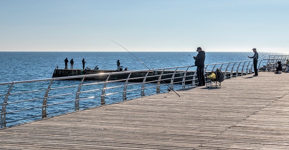 Odessa, Ukraine 28.10.2022. Fishermen on the pier of the Lanzheron embankment in Odessa, Ukraine, on a sunny autumn day
