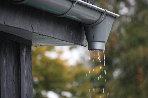 A closeup shot of water drops falling from rain gutters