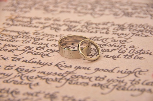 A closeup shot of silver wedding rings on wedding vow papers