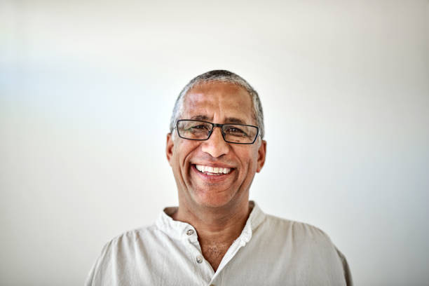 hombre mayor feliz, retrato de sonrisa con fondo de pared blanco y relájese sentado en casa con gafas. jubilación de ancianos, vieja felicidad y hombre negro seguro con cara orgullosa, en casa o en un hogar de ancianos - men middle senior adult human age fotografías e imágenes de stock