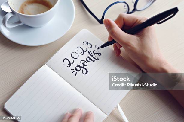 Businesswomen Writing 2023 Goals On Notebook For New Year Resolution Plan Stock Photo - Download Image Now