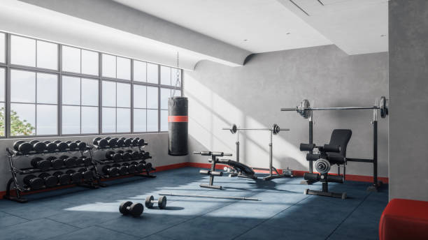 Weight Training Equipment In A Modern Gym Interior of an empty modern gym fitness room with large windows. gym stock pictures, royalty-free photos & images
