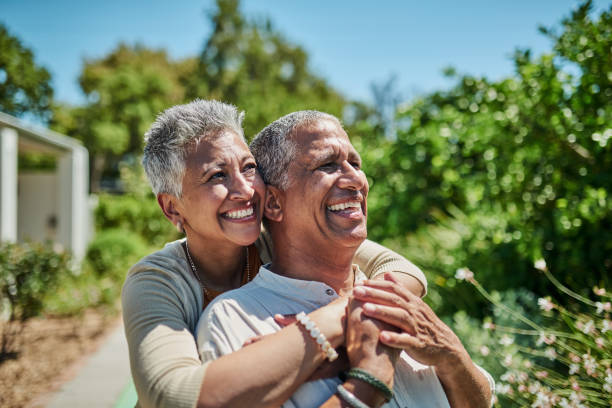 le jardin, la retraite à domicile et le couple de personnes âgées s’étreignent pour la santé, la richesse et le bien-être en été avec un ciel bleu et des arbres. des personnes âgées enthousiastes avec amour, soins et soutien dans la cour arriè - senior adult outdoors wellbeing sky photos et images de collection