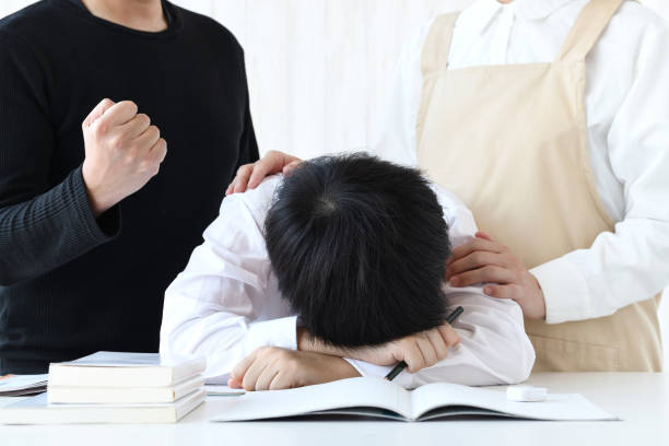 Boy lying face down on desk and encouraging parents