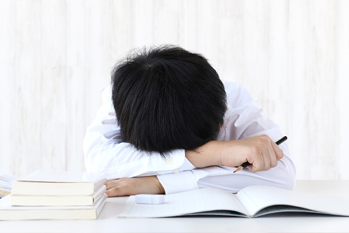 Boy lying face down on desk, he doesn't want to study anymore