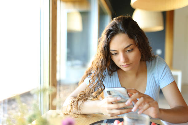 istock Woman using cell phone in a restaurant 1437853832