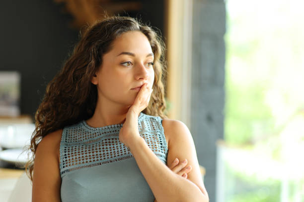 istock Pensive woman looking through a window 1437853939