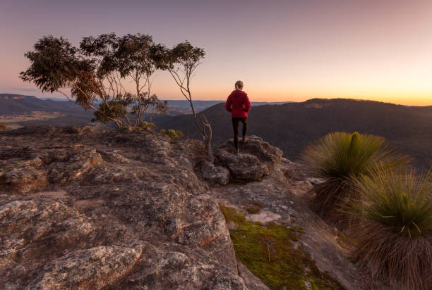 istock Woman standing on rocky mountain  ledge at sunset 1437853974