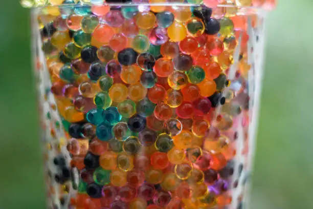 Close up on a glass filled with colored balls. Strong bokeh.
