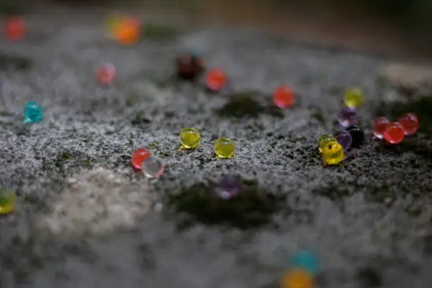 Close up on colored balls on a stone floor with moss. Tilt shift effect, focus on central balls.