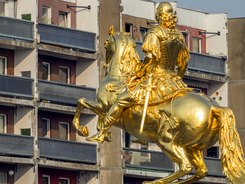 Dresden, Germany - August 10, 2015: Equestrian statue in front of a socialist prefabricated building. Equestrian statue of the Saxon Elector and Polish King August the Strong on the Neustädter Markt in Dresden between Augustus Bridge and the main street. Gold leaf was used for the 1956 restoration. 1732 to 1734 embossed in copper and fire-gilded by Ludwig Wiedemann.