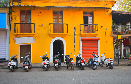 Scooters parked in front of a yellow house at fontainhas area in Panaji, Goa.