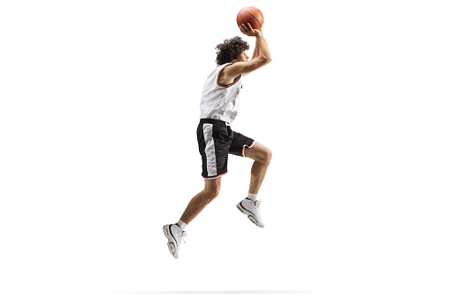 Full length shot of a basketball player up in the air shooting a ball isolated on white background