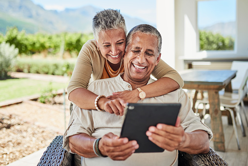 Outdoor, online and senior couple using a tablet for video call, internet and social media. Mature black man and woman with digital tech for chatting, phone call and texting on retirement home patio