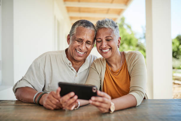 telefon, videoanruf und älteres paar entspannen sich im hinterhof, verbinden sich und lachen über online-gespräche. glückliche familie, reifer mann und frau, die telefonieren, während sie auf der terrasse sitzen, ruhestand lebensstil - senior adult retirement mature adult couple stock-fotos und bilder