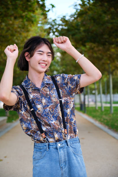 istock Asian guy smiling and dancing rock and roll in a park. 1437860276